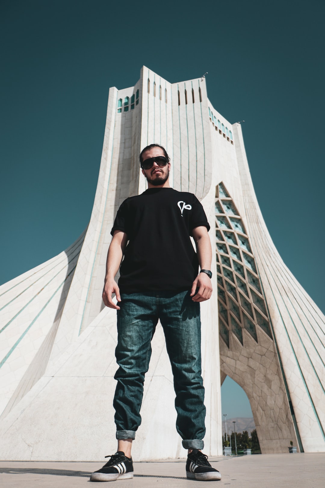 man in black crew neck t-shirt and blue denim jeans standing near white concrete building