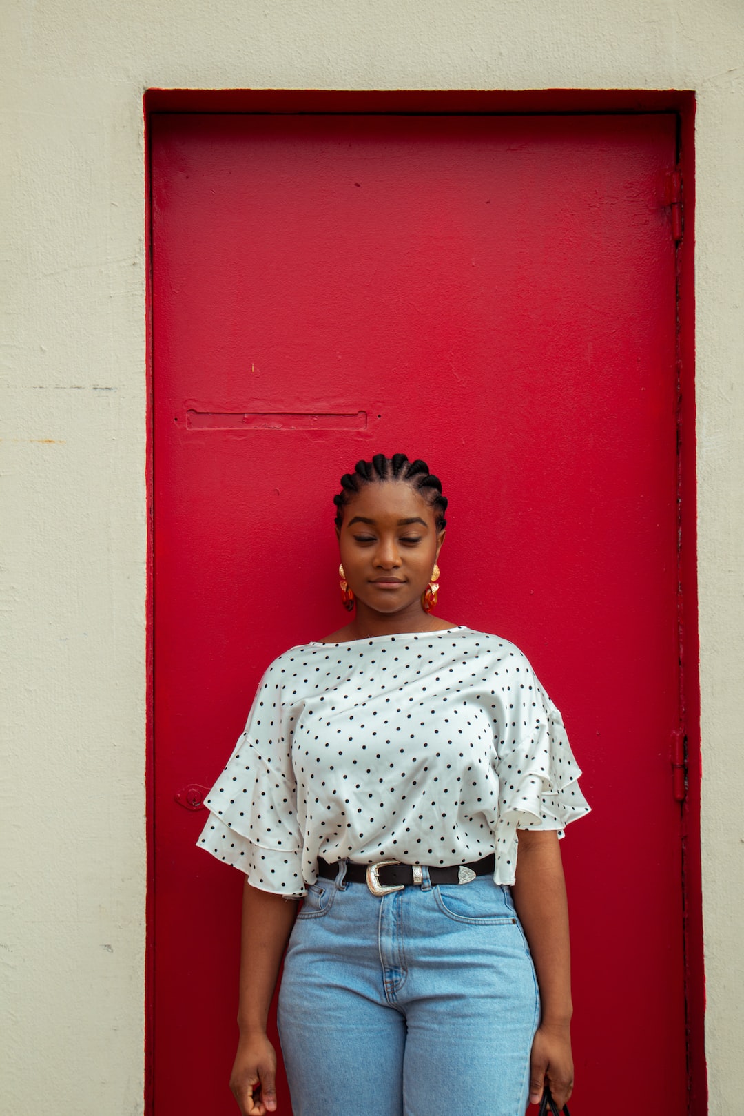 girl in white and red floral shirt standing beside red wall