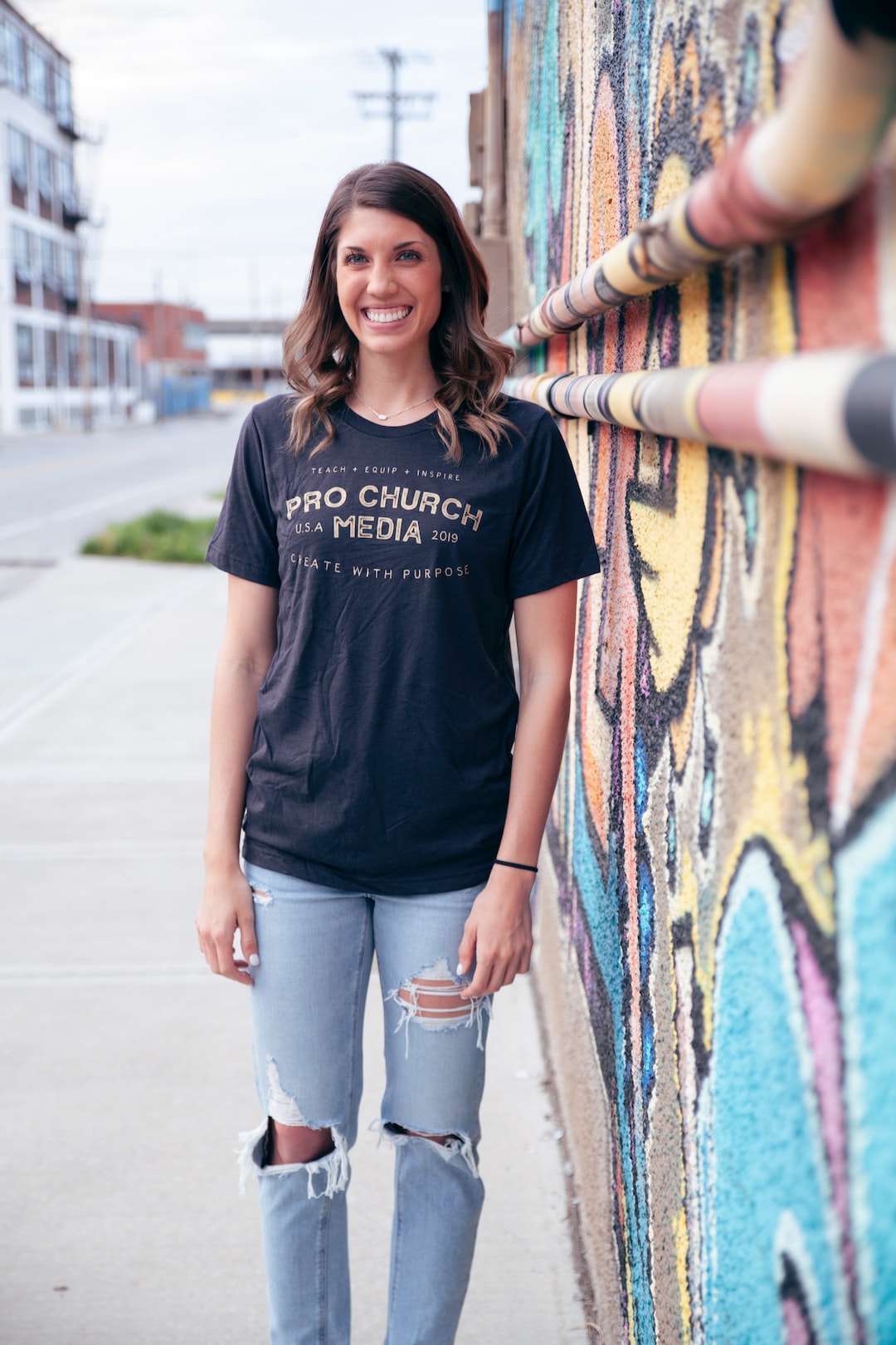 woman in black crew neck t-shirt and blue denim jeans standing beside wall with graffiti