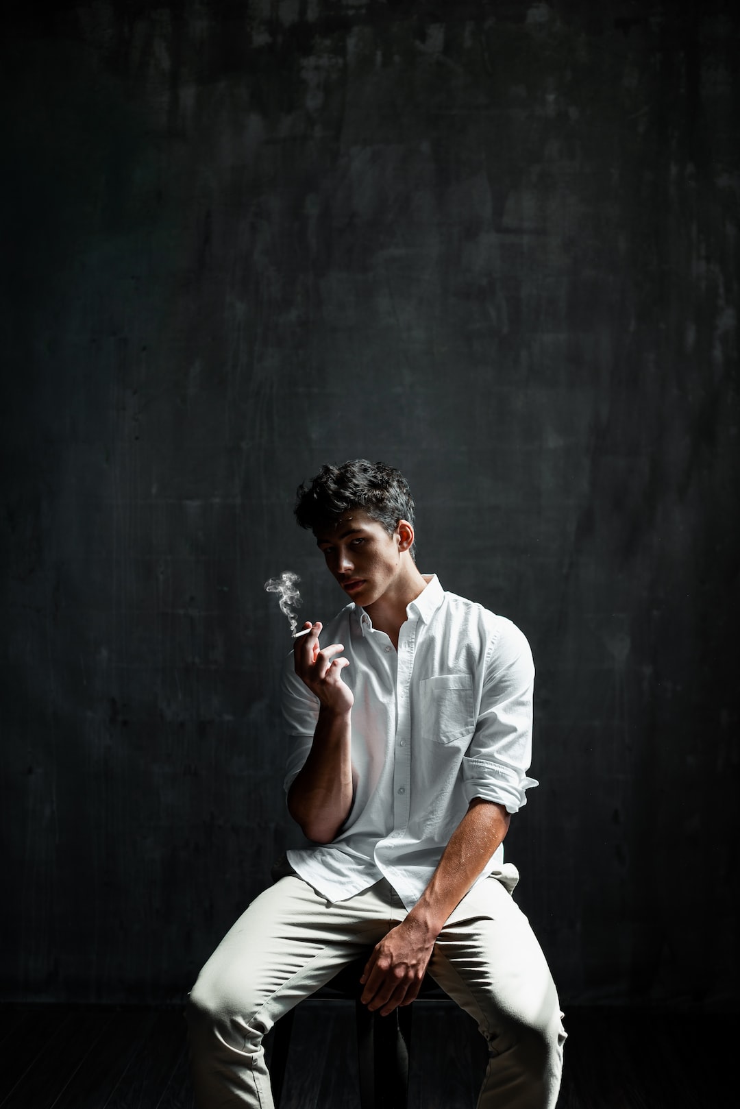 man sitting on chair smoking cigar