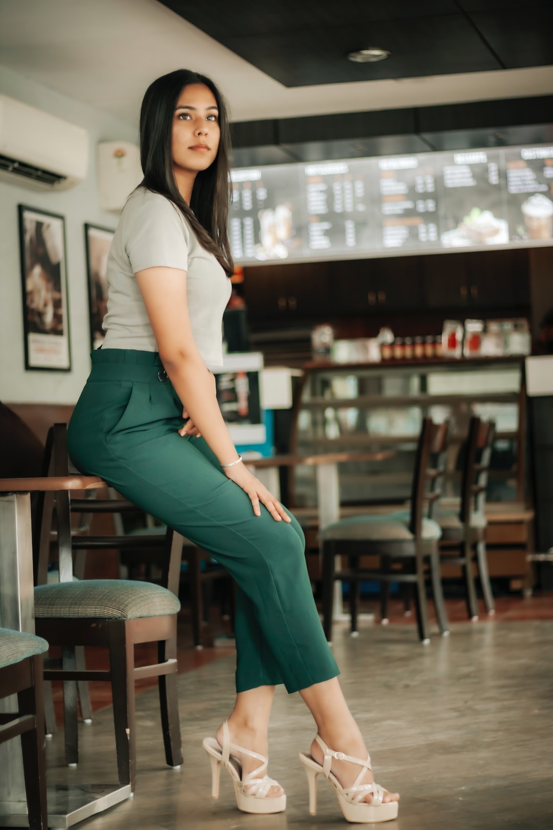 woman in white shirt and green pants sitting on bar seat