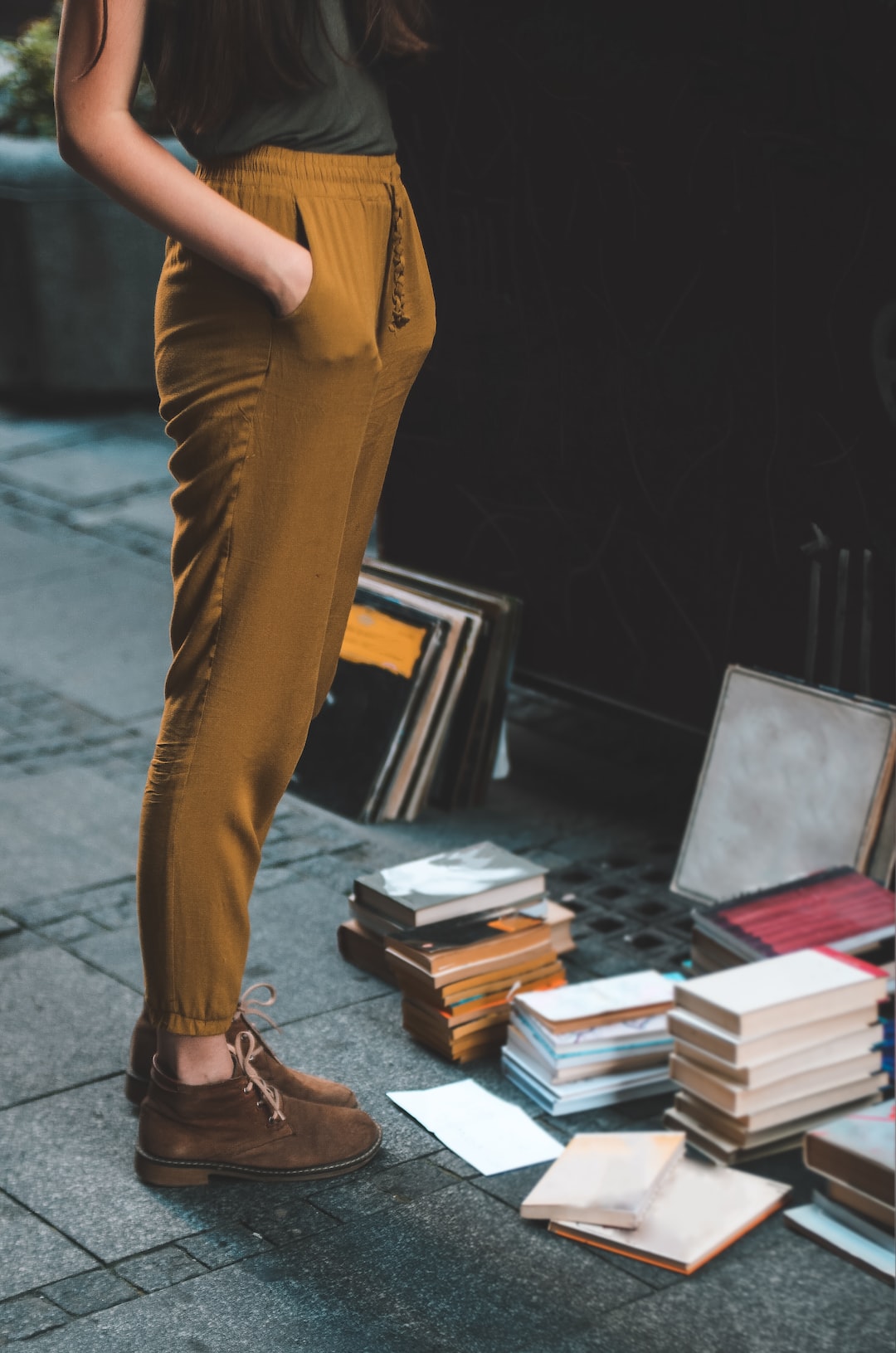 person wearing brown pants beside assorted book lot