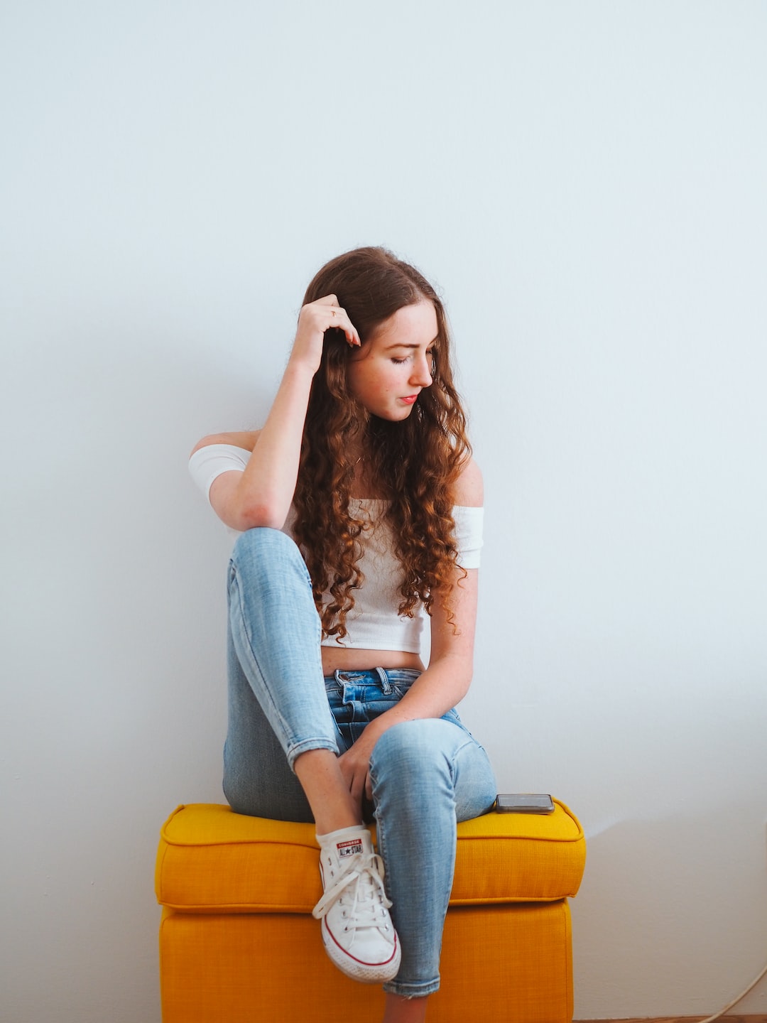 woman in blue denim jeans sitting on yellow chair