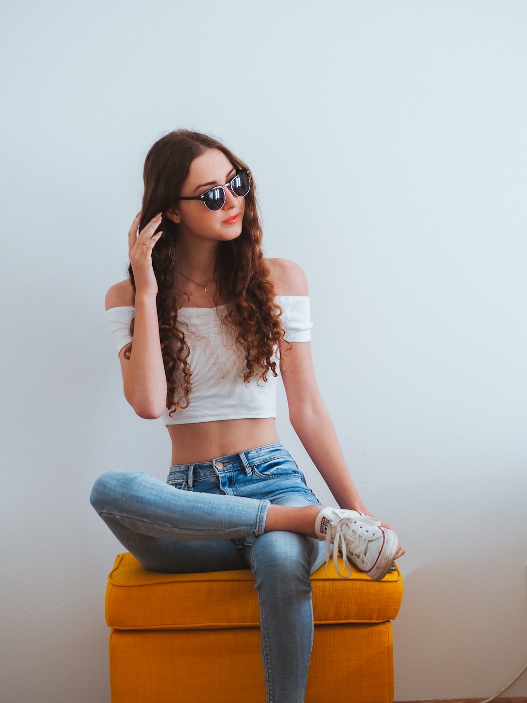 woman in white crop top and blue denim jeans wearing black sunglasses