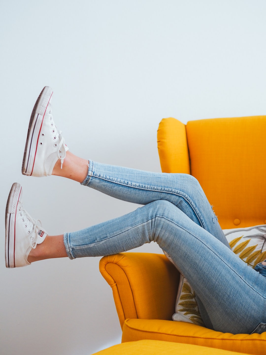 woman in blue denim jeans and white converse all star high top sneakers sitting on orange