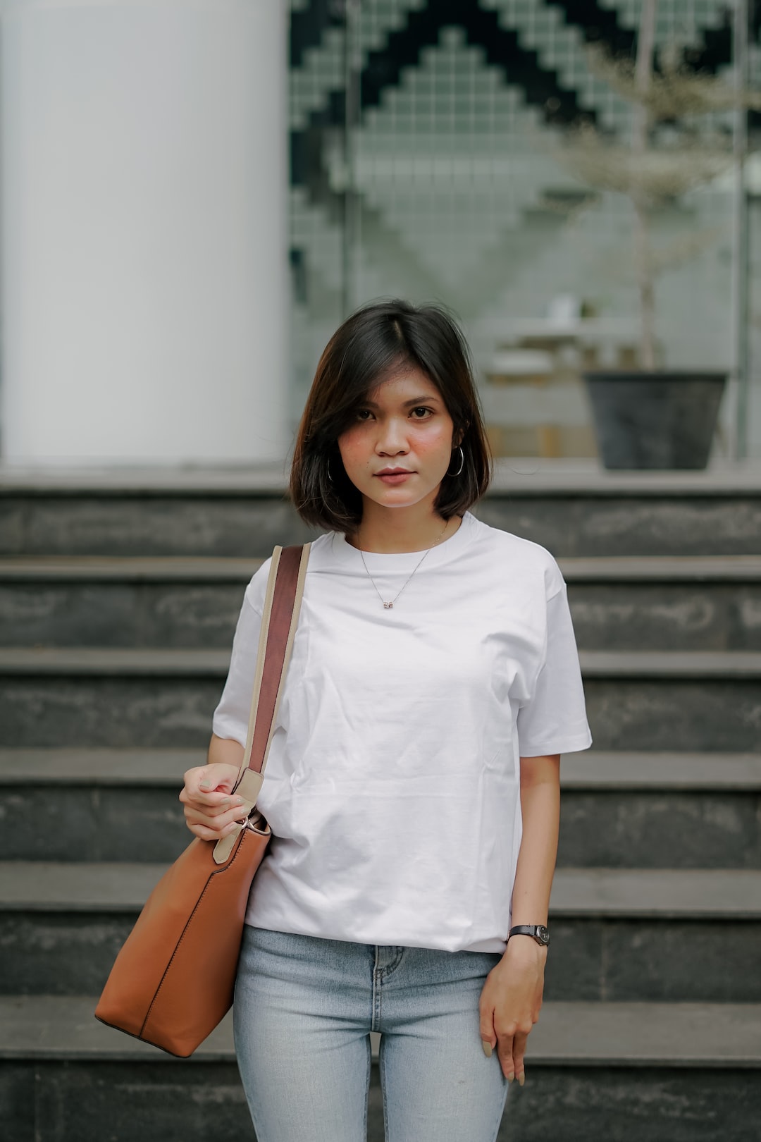 woman in white crew neck t-shirt and brown leather sling bag