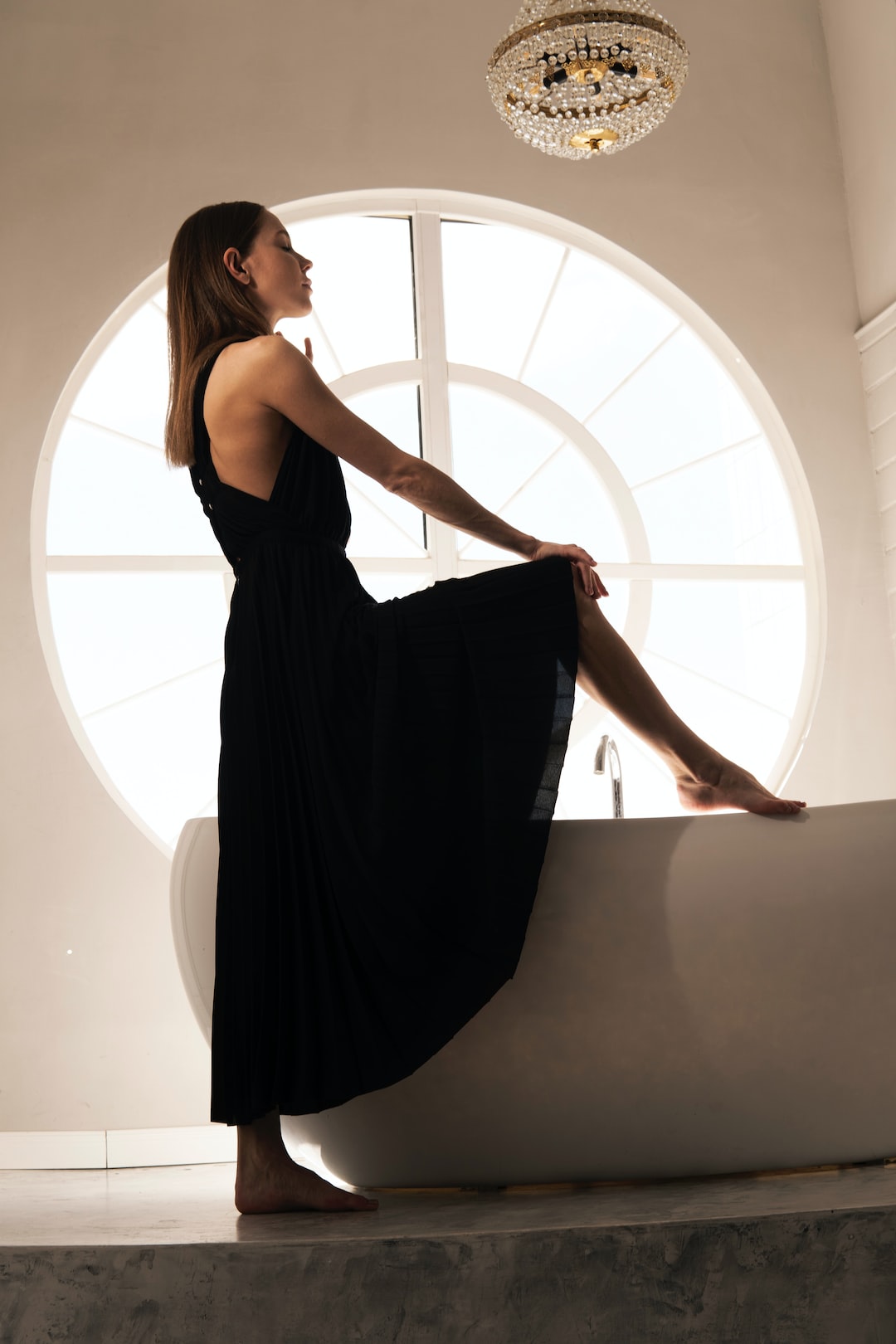 woman in black sleeveless dress standing on white window