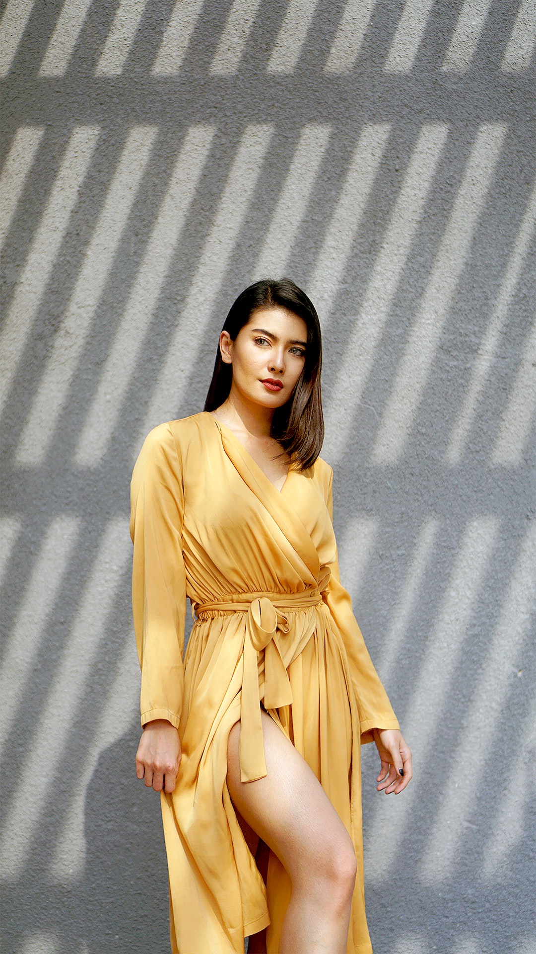 woman in brown long sleeve dress standing beside gray wall