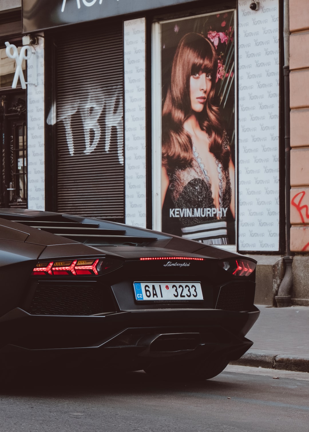 black Lamborghini beside Kevin Murphy poster